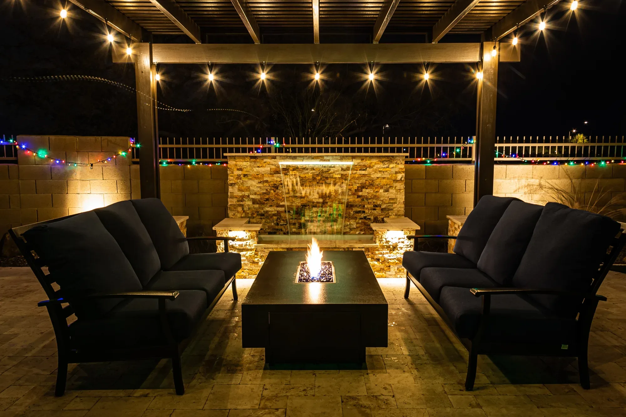 Fire pit table with lit gas flame under a pergola