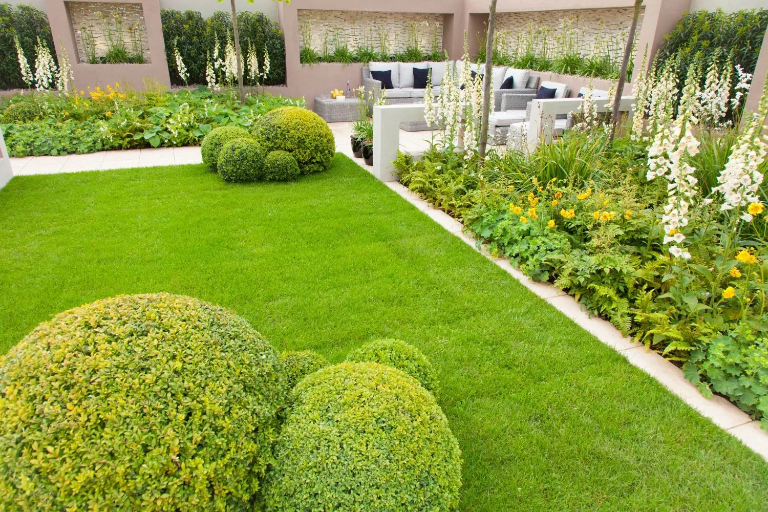 Backyard garden with topiary hedges and a paved outdoor lounge area