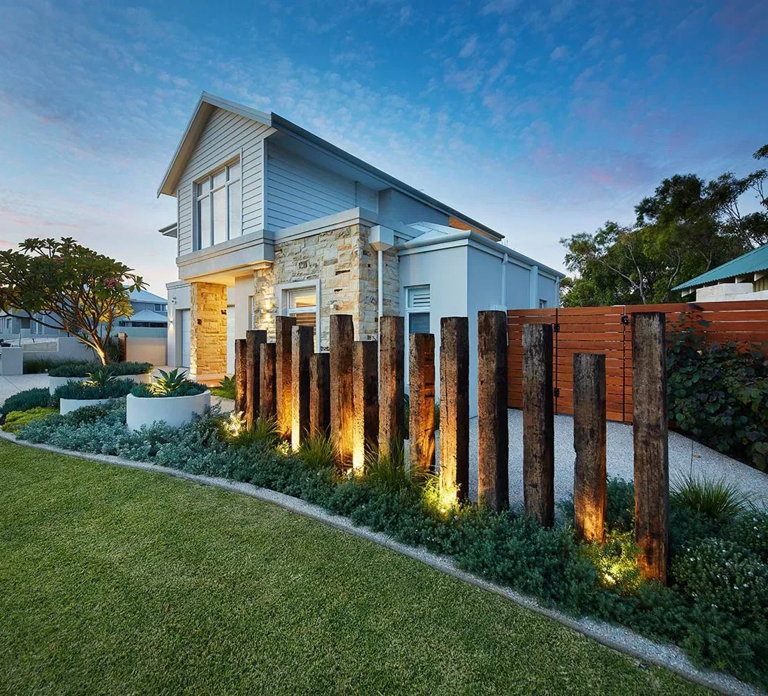 Front garden with timber sleeper feature posts and garden lighting at dusk