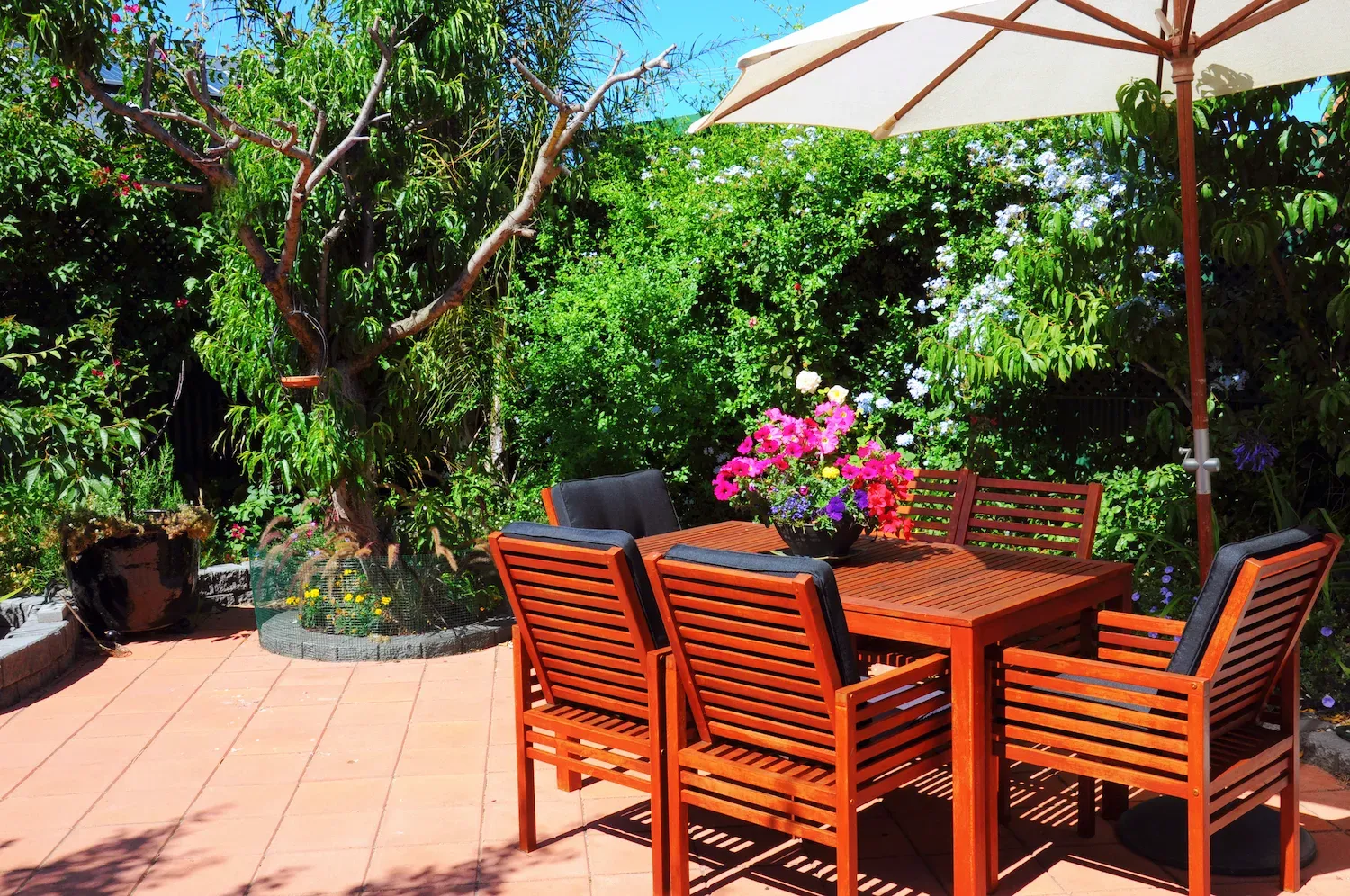 Shaded patio dining area with umbrella surrounded by garden