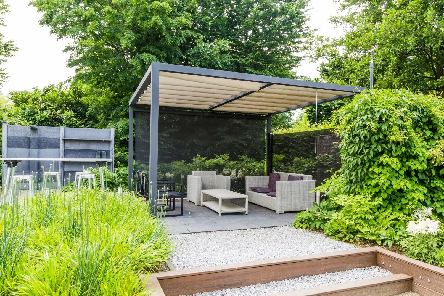 Covered outdoor room with shade sail and lounge seating in a landscaped garden