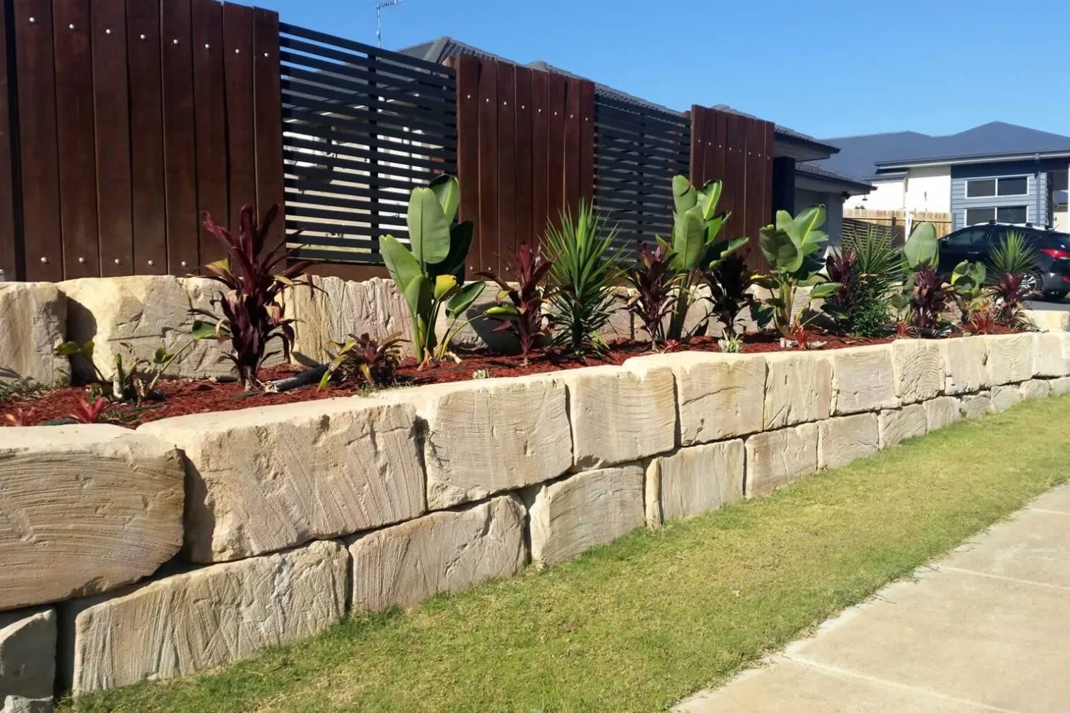 Sandstone block retaining wall with tropical garden bed planting